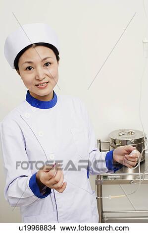 Picture - Portrait of a female nurse holding an iv drip. Fotosearch