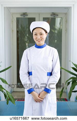 Stock Photo - Portrait of a female nurse standing and smiling. Fotosearch