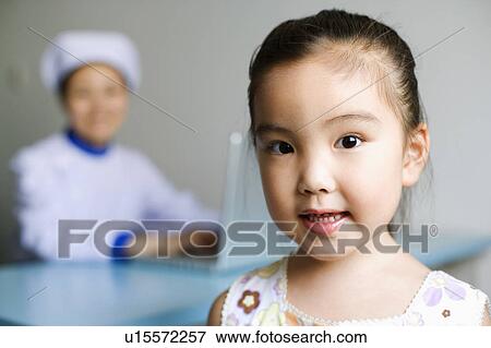 Stock Photo - Portrait of a girl and a nurse working on a laptop in the background. Fotosearch