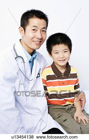 Portrait of a male doctor and a boy sitting together View Large Photo Image Stock Photo - Portrait of a male doctor and a boy sitting together. Fotosearch