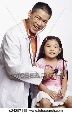Portrait of a male doctor examining his patient with a stethoscope View Large Photo Image Stock Photo - Portrait of a male doctor examining his patient with a stethoscope. Fotosearch
