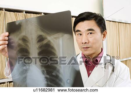 Stock Image - Portrait of a male doctor holding an X-Ray. Fotosearch