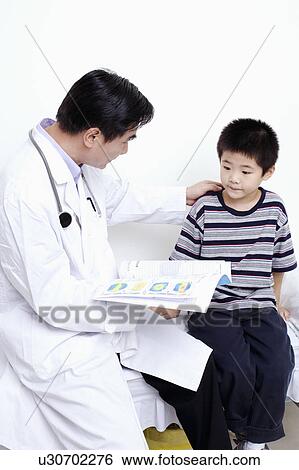 Stock Photograph - Side profile of a doctor holding the report of a child. Fotosearch