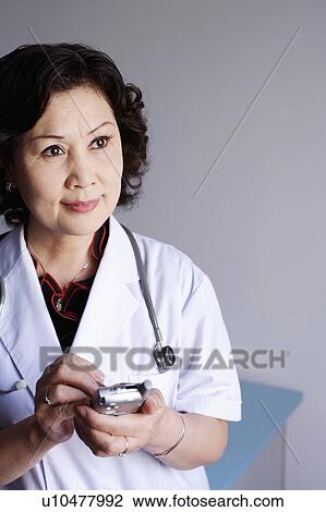 Stock Image - Close-up of a female doctor holding a personal data assistant. Fotosearch