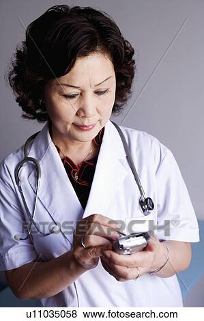 Close-up of a female doctor holding a personal data assistant View Large Photo Image Stock Photo - Close-up of a female doctor holding a personal data assistant. Fotosearch