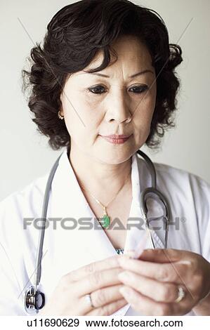 Stock Photo - Close-up of a female doctor holding a syringe. Fotosearch