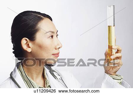 Stock Photograph - Close-up of a female doctor holding a graduated cylinder. Fotosearch