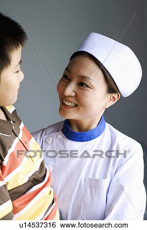 Stock Photograph - Close-up of a female nurse and a boy smiling and looking at each other. Fotosearch