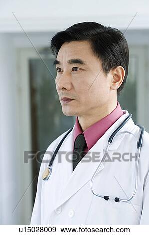 Stock Photo - Close-up of a male doctor standing and looking away. Fotosearch