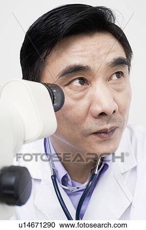 Close-up of an optometrist in front of an ophthalmoscope View Large Photo Image Stock Image - Close-up of an optometrist in front of an ophthalmoscope. Fotosearch