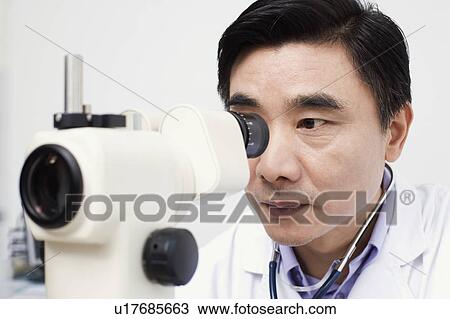 Close-up of an optometrist looking into an ophthalmoscope View Large Photo Image Stock Image - Close-up of an optometrist looking into an ophthalmoscope. Fotosearch