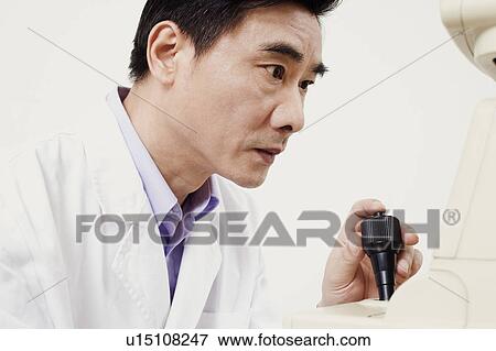 Stock Photo - Close-up of an optometrist operating an ophthalmoscope. Fotosearch