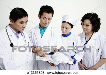 Close-up of two male doctors and a female doctor with a female nurse discussing a report View Large Photo Image Stock Photo - Close-up of two male doctors and a female doctor with a female nurse discussing a report. Fotosearch