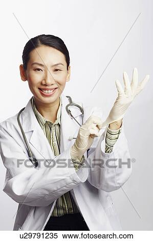 Portrait of a female doctor putting on surgical gloves View Large Photo Image Stock Photography - Portrait of a female doctor putting on surgical gloves. Fotosearch