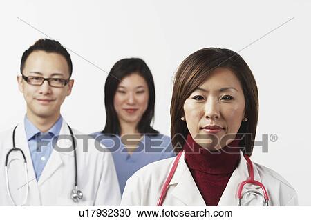 Stock Image - Portrait of a female doctor with a male doctor and a female nurse standing behind her. Fotosearch