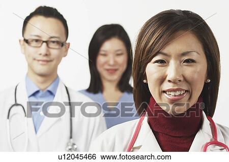 Stock Photograph - Portrait of a female doctor with a male doctor and a female nurse standing behind her. Fotosearch