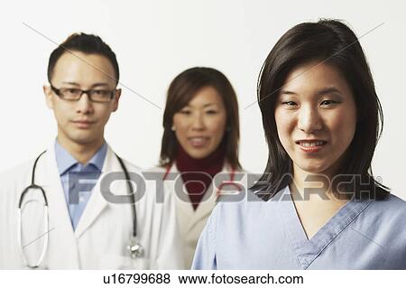 Portrait of a female nurse with two doctors standing behind her View Large Photo Image Stock Photo - Portrait of a female nurse with two doctors standing behind her. Fotosearch