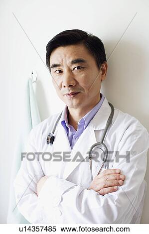 Stock Photography - Portrait of a male doctor leaning against a wall. Fotosearch