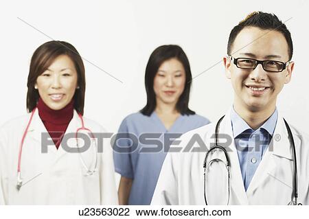 Stock Image - Portrait of a male doctor with a female doctor and a female nurse standing behind him. Fotosearch