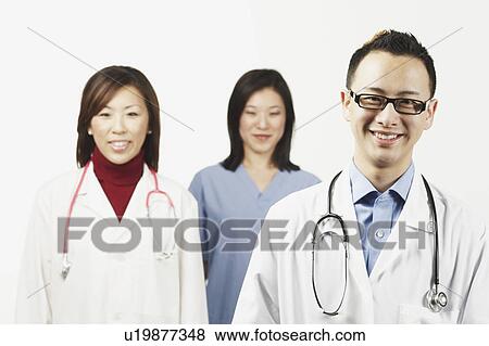 Portrait of a male doctor with a female doctor and a female nurse standing behind him View Large Photo Image Stock Photo - Portrait of a male doctor with a female doctor and a female nurse standing behind him. Fotosearch