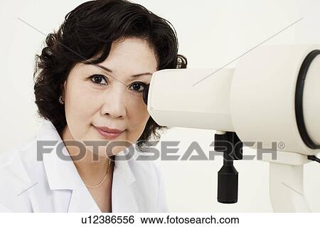 Stock Photograph - Portrait of an optometrist in front of an ophthalmoscope. Fotosearch