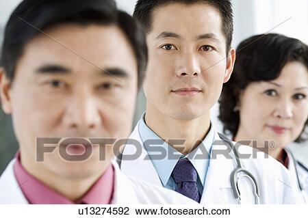 Stock Image - Portrait of two male doctors with a female doctor. Fotosearch