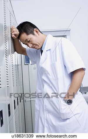 Close-up of a doctor leaning against a locker View Large Photo Image Stock Photo - Close-up of a doctor leaning against a locker. Fotosearch