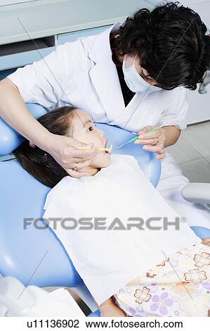 Close-up of a female dentist examining a girl's teeth View Large Photo Image Stock Image - Close-up of a female dentist examining a girl's teeth. Fotosearch