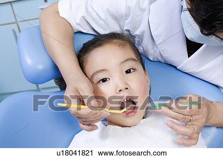 Close-up of a female dentist examining a girl's teeth View Large Photo Image Stock Image - Close-up of a female dentist examining a girl's teeth. Fotosearch