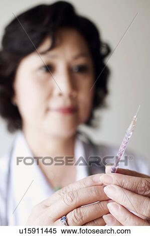 Stock Photography - Close-up of a female doctor holding a syringe. Fotosearch