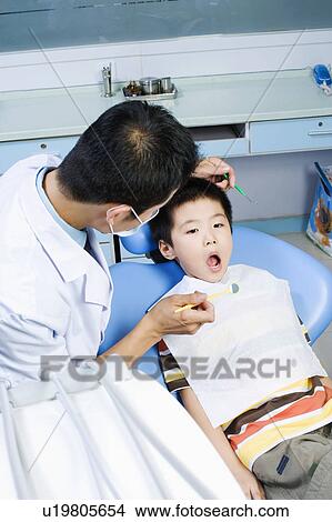 Close-up of a male dentist examining a boy's teeth View Large Photo Image Picture - Close-up of a male dentist examining a boy's teeth. Fotosearch