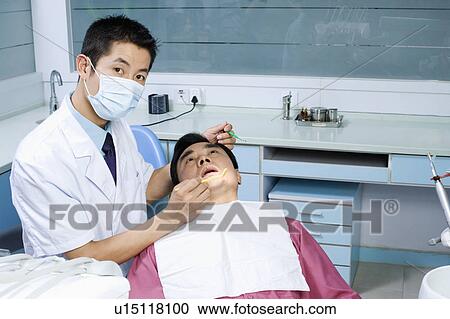 Close-up of a male dentist examining a male patient View Large Photo Image Stock Image - Close-up of a male dentist examining a male patient. Fotosearch