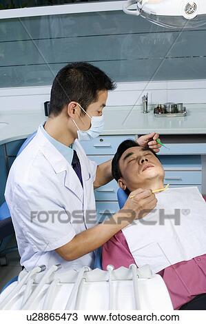 Close-up of a male dentist examining a male patient View Large Photo Image Stock Image - Close-up of a male dentist examining a male patient. Fotosearch