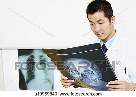 Stock Image - Close-up of a male doctor examining an X-Ray. Fotosearch