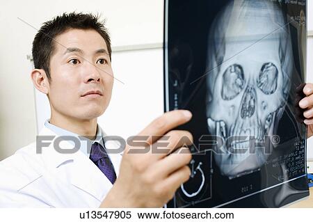 Stock Photography - Close-up of a male doctor holding an X-Ray image. Fotosearch