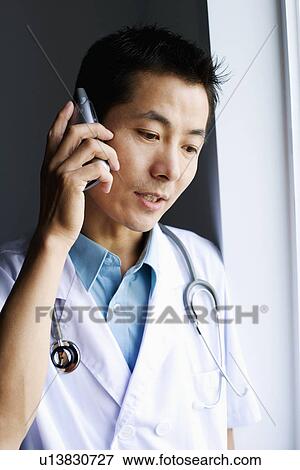 Close-up of a male doctor talking on a mobile phone View Large Photo Image Stock Photo - Close-up of a male doctor talking on a mobile phone. Fotosearch