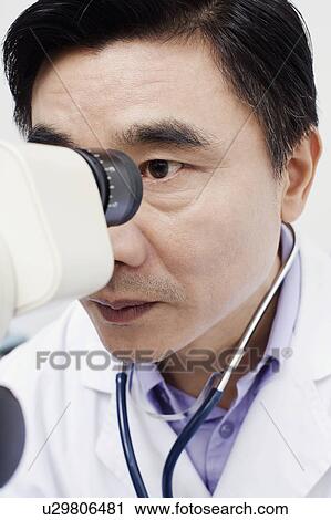 Stock Image - Close-up of an optometrist looking into an ophthalmoscope. Fotosearch