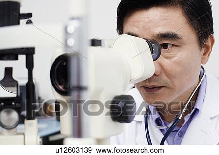 Close-up of an optometrist looking into an ophthalmoscope View Large Photo Image Stock Photo - Close-up of an optometrist looking into an ophthalmoscope. Fotosearch