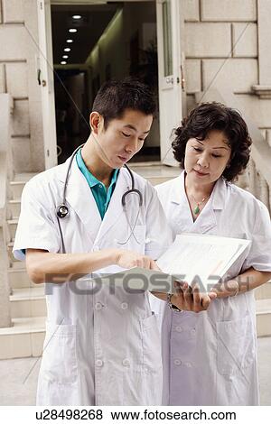 Male doctor and a female doctor discussing a report View Large Photo Image Stock Photo - Male doctor and a female doctor discussing a report. Fotosearch