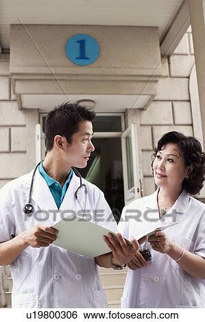 Stock Photograph - Male doctor and a female doctor discussing a report. Fotosearch