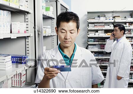 Male pharmacist holding medicine in a store room View Large Photo Image Stock Image - Male pharmacist holding medicine in a store room. Fotosearch