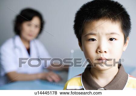 Portrait of a boy with a female doctor working on a laptop in the background View Large Photo Image Stock Photo - Portrait of a boy with a female doctor working on a laptop in the background. Fotosearch