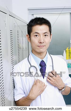 Portrait of a doctor standing and holding a stethoscope View Large Photo Image Stock Photo - Portrait of a doctor standing and holding a stethoscope. Fotosearch
