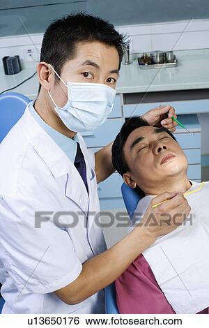 Stock Photograph - Portrait of a male doctor while examining a male patient. Fotosearch