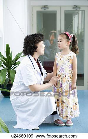 Side profile of a female doctor smiling with a girl standing beside her View Large Photo Image Stock Photo - Side profile of a female doctor smiling with a girl standing beside her. Fotosearch