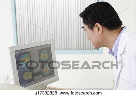 Side profile of a male doctor looking at a computer monitor View Large Photo Image Stock Photo - Side profile of a male doctor looking at a computer monitor. Fotosearch