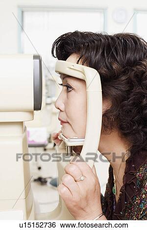 Stock Photograph - Side profile of a patient being examined with an ophthalmoscope. Fotosearch