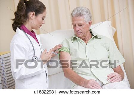 Stock Image - Doctor giving man needle in exam room. Fotosearch