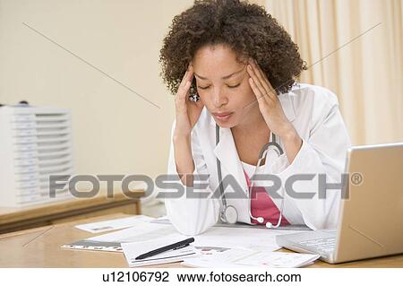 Doctor with laptop and headache in doctor's office View Large Photo Image Stock Image - Doctor with laptop and headache in doctor's office. Fotosearch