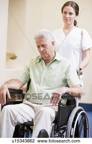 Stock Image - Nurse Pushing Man In Wheelchair. Fotosearch